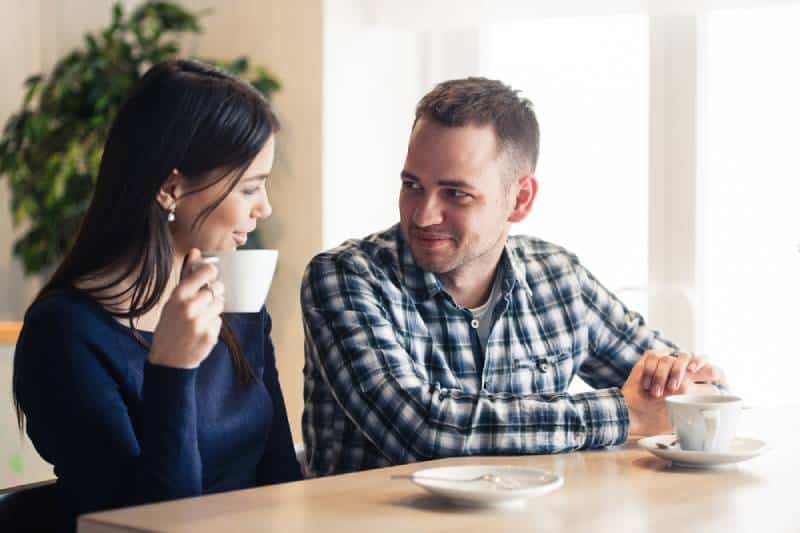 man and woman talking at cafe and drinking tea