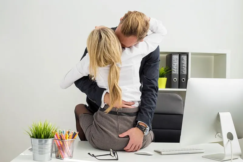 man kissing with woman in the office