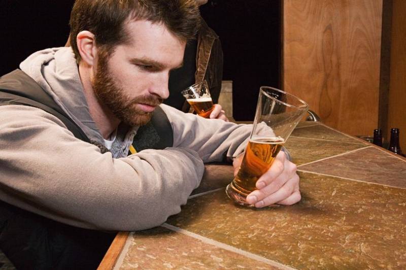 man looking at glass of beer