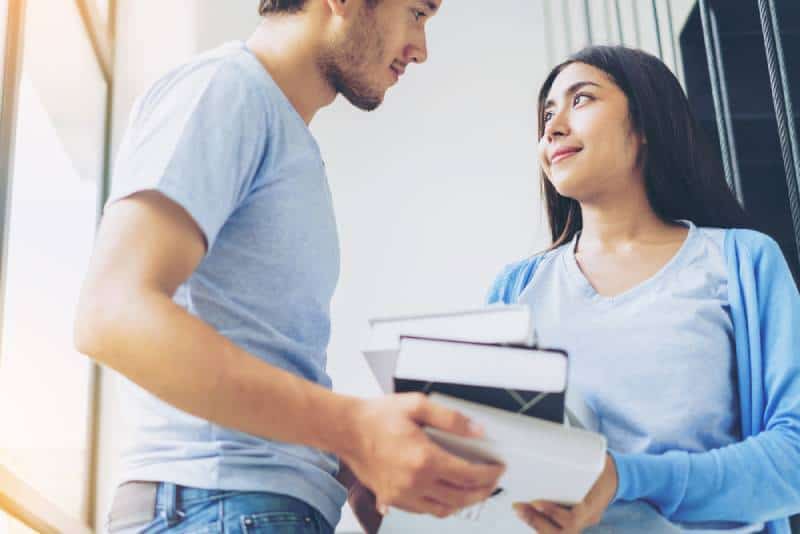 man picked up books to woman while looking at each other