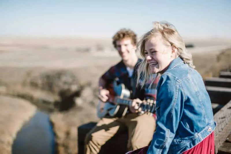 man playing guitar beside smiling girl