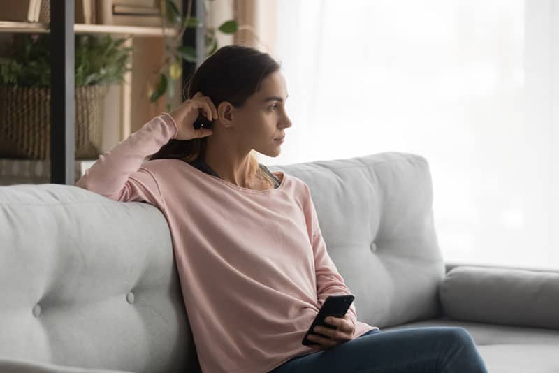 Donna pensierosa con in mano un cellulare