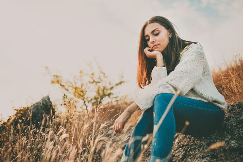 chica triste sentada sola en la naturaleza