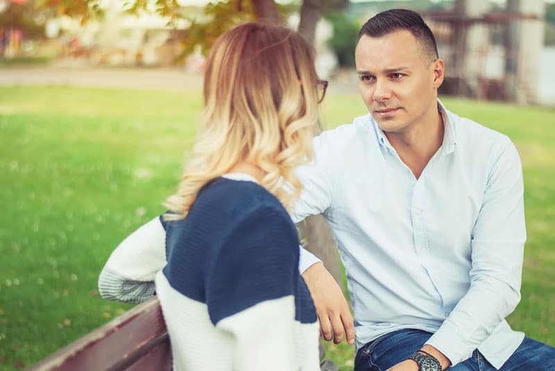 uomo timido che ascolta la donna sulla panchina