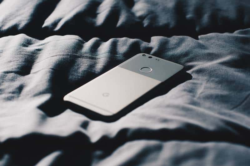 silver smartphone on bed