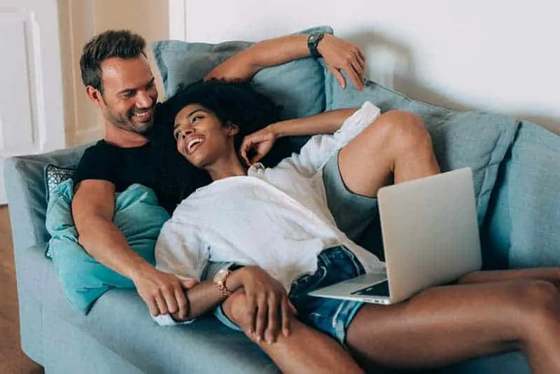 smiling couple lying on couch together
