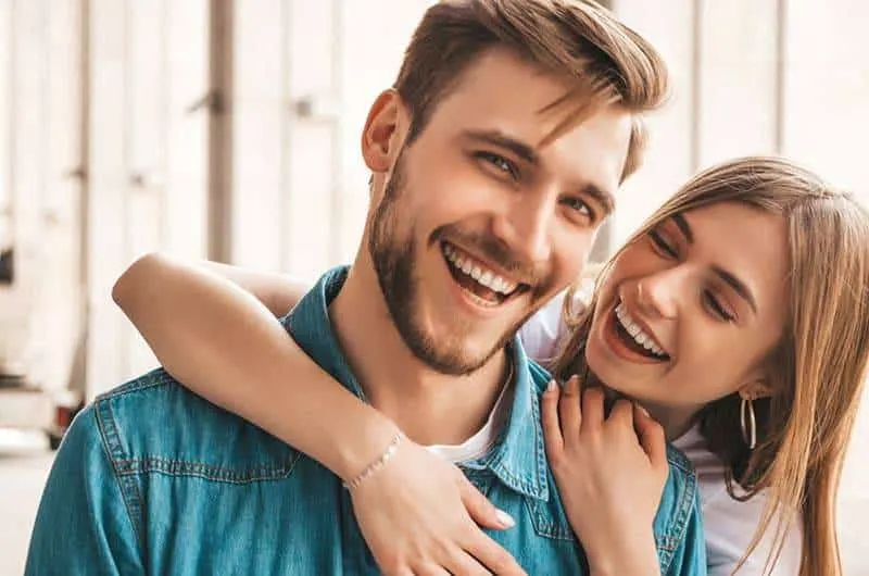 smiling woman hugging happy man from back