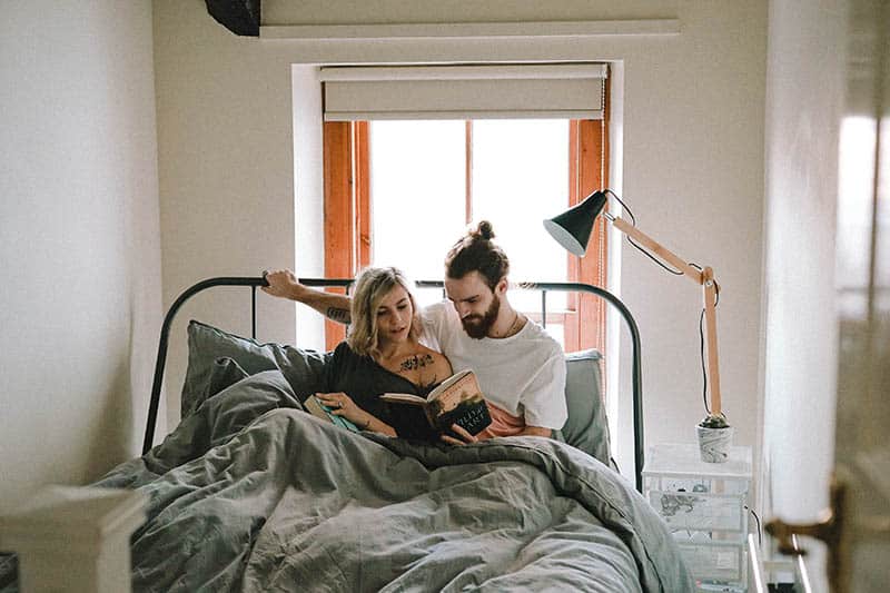Couple lying in bed reading a book