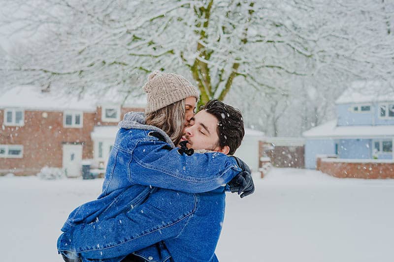 Uomo che tiene in braccio una donna sulla neve