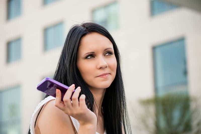 mulher a segurar o telefone no exterior