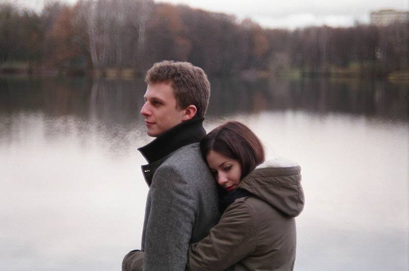 donna che abbraccia un uomo di spalle accanto al lago