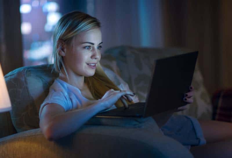 mujer mirando portátil por la noche en la sala de estar