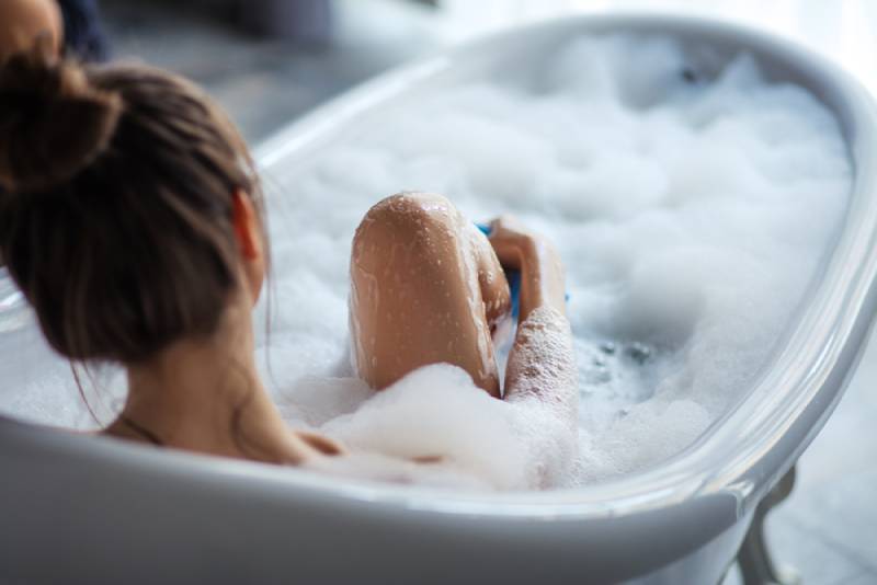 mujer masajeando su pierna en la bañera