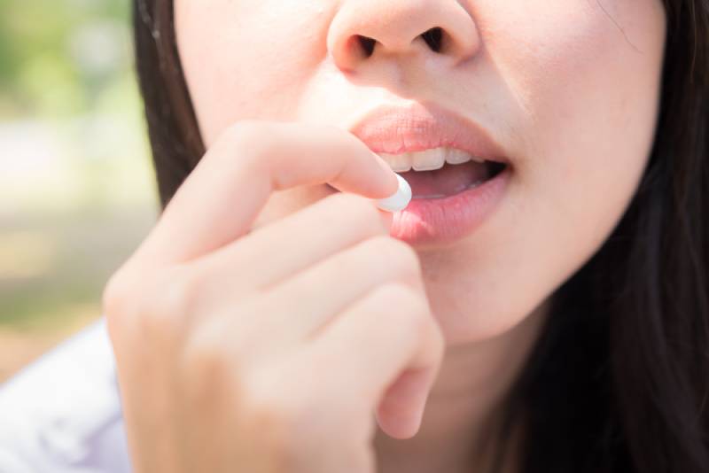 woman putting pill in mouth