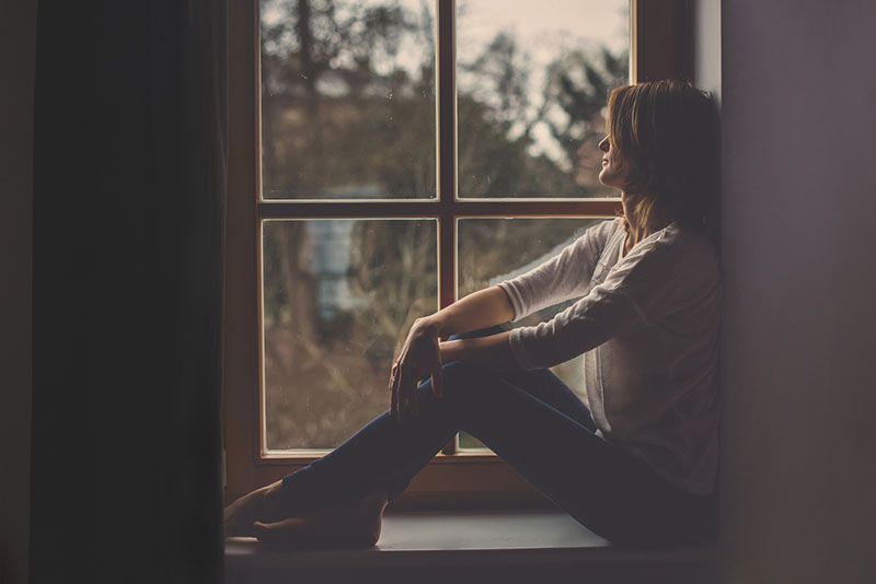 mujer sentada junto a la ventana