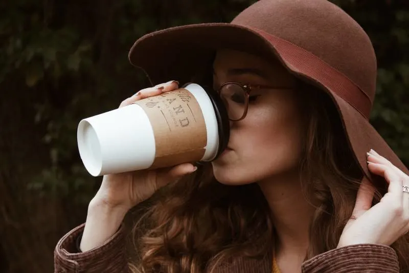 woman wearing brown hat and drinking coffee from cup