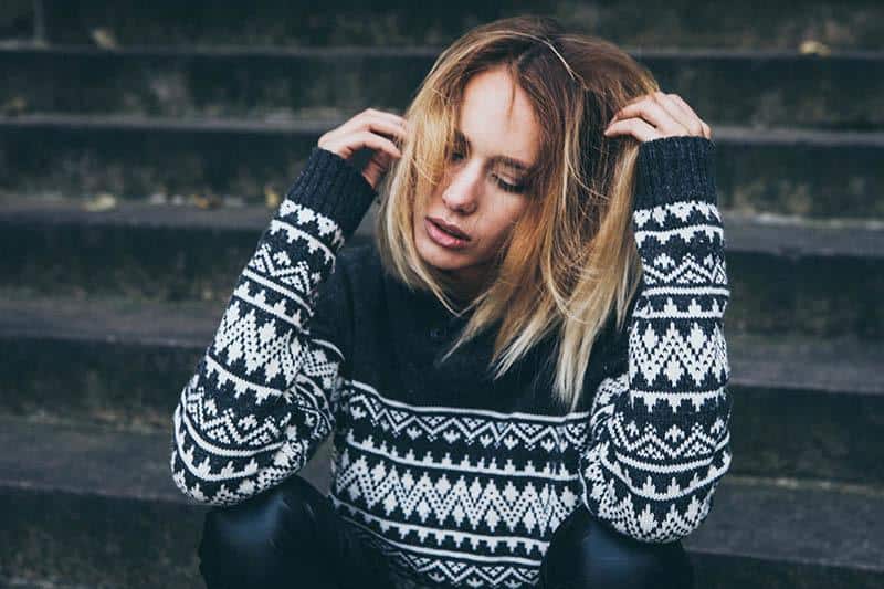 worried woman in sweatshirt sitting on stairs outside