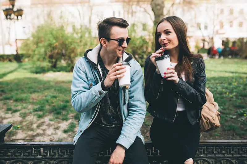 young couple drinking coffee in the park