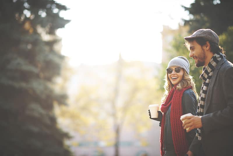 joven pareja caminando y sosteniendo tazas de café