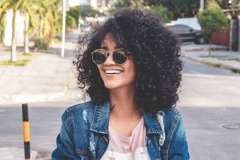 afro woman wearing sunglasses and smiling outside