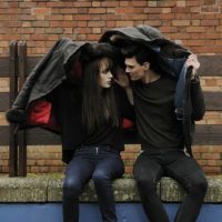 man and woman sitting outside under covered with jacket