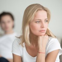 the sad blonde thinks and sits on the sofa in front of her man