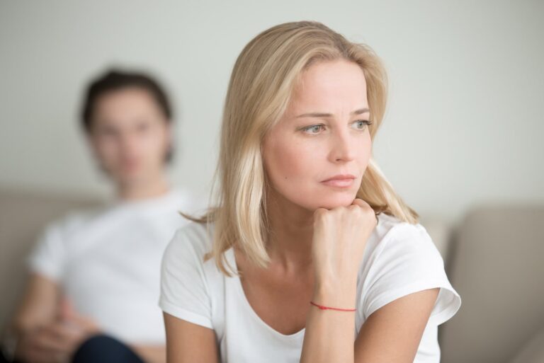 the sad blonde thinks and sits on the sofa in front of her man