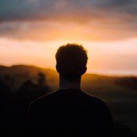 silhouette of man facing sunset