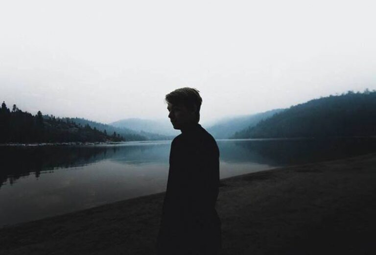 silhouette of man standing in front of water