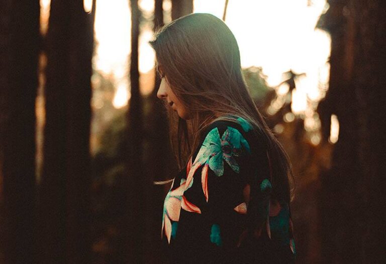 sad view of young brunette beside trees