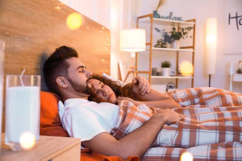 Pareja joven y feliz durmiendo en la cama por la noche