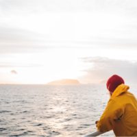 man wearing red hat and yellow raincoat floating on ship