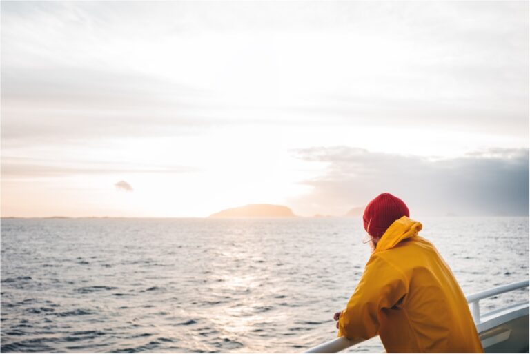 man wearing red hat and yellow raincoat floating on ship
