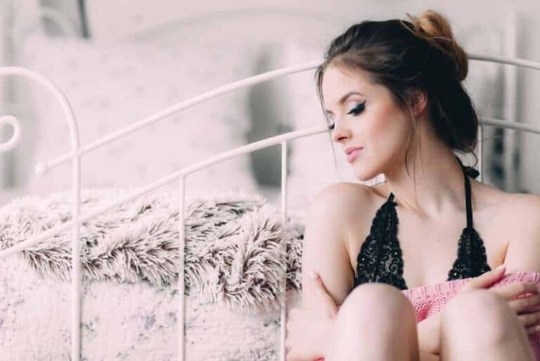 woman wearing bra while sitting on bed