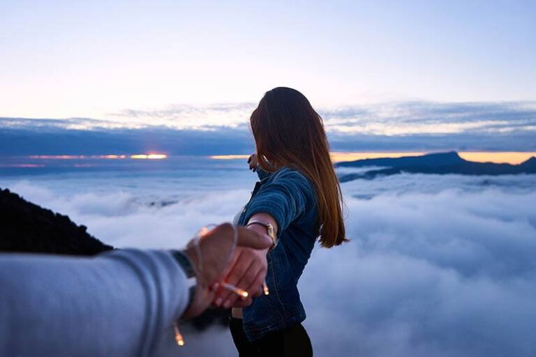 man holds woman's hand while she facing the sky