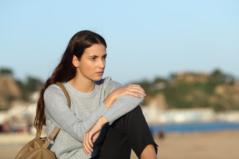 woman looking away sitting on a coast town beach