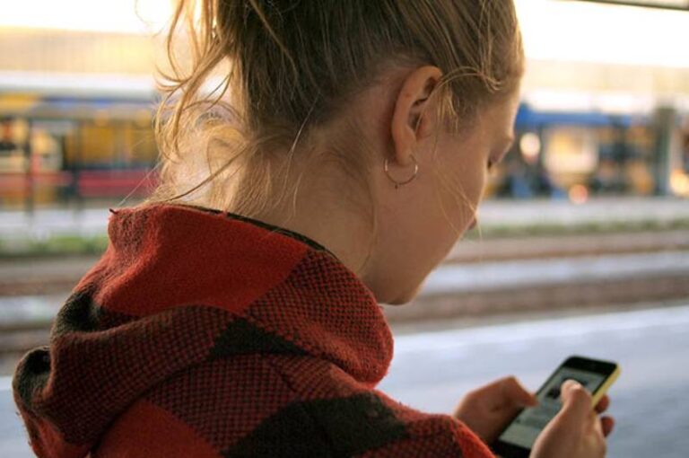 side view of woman wearing shirt and typing on her phone
