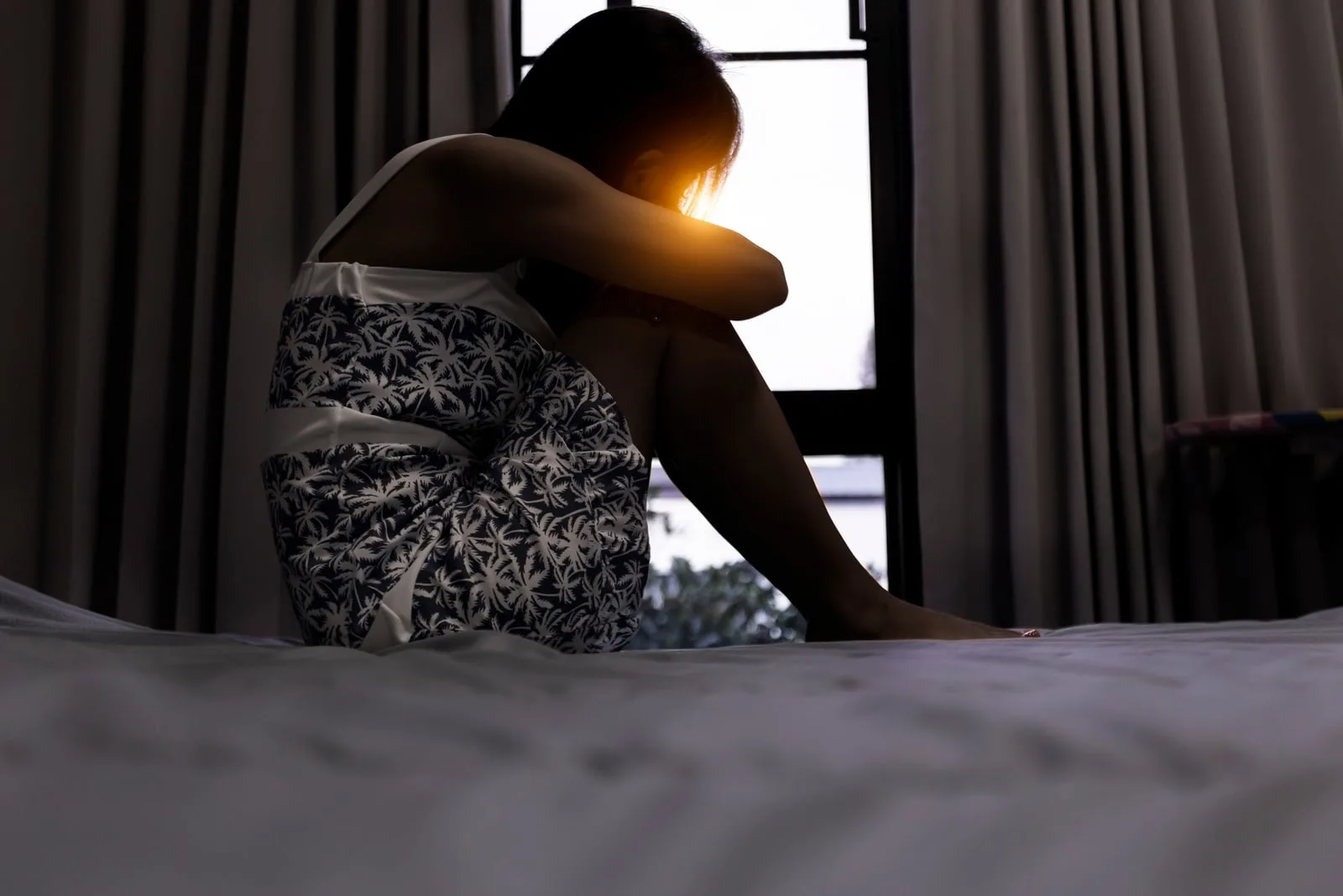 a sad woman in a nightgown is sitting on the bed