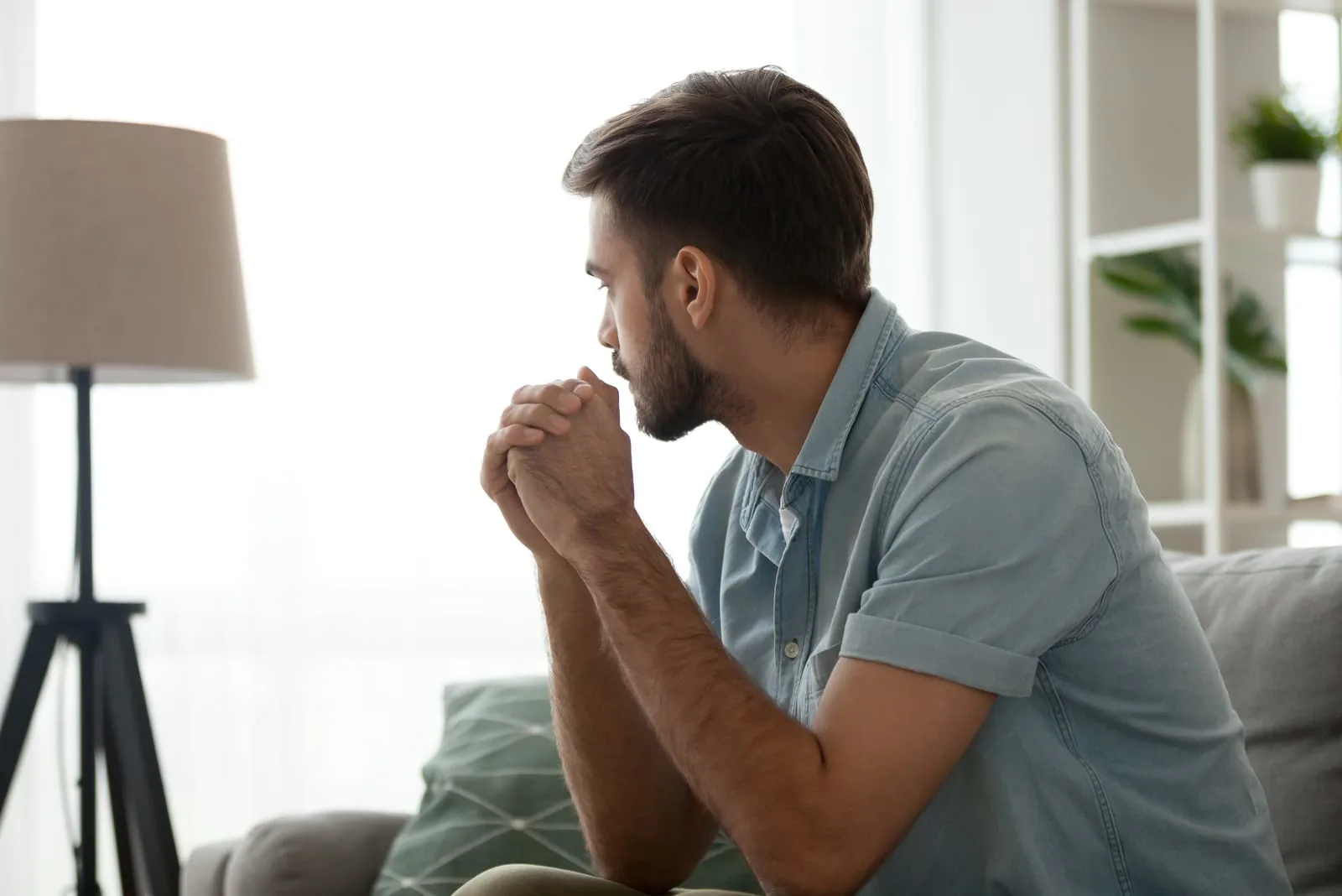 a serious bearded man sits on the sofa and thinks