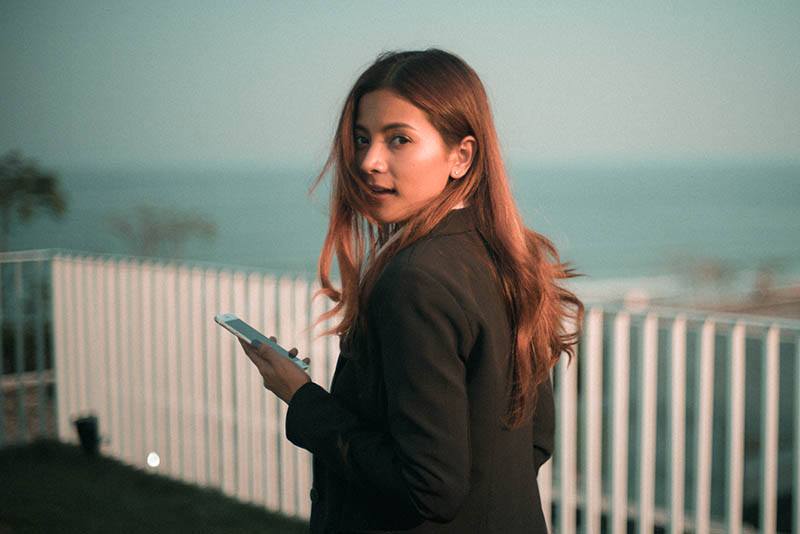 mulher atraente a segurar o telemóvel ao ar livre