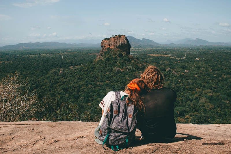 vista traseira de um casal sentado no cimo de uma colina