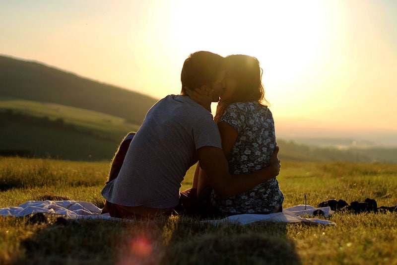 coppia che si bacia sull'erba all'aperto