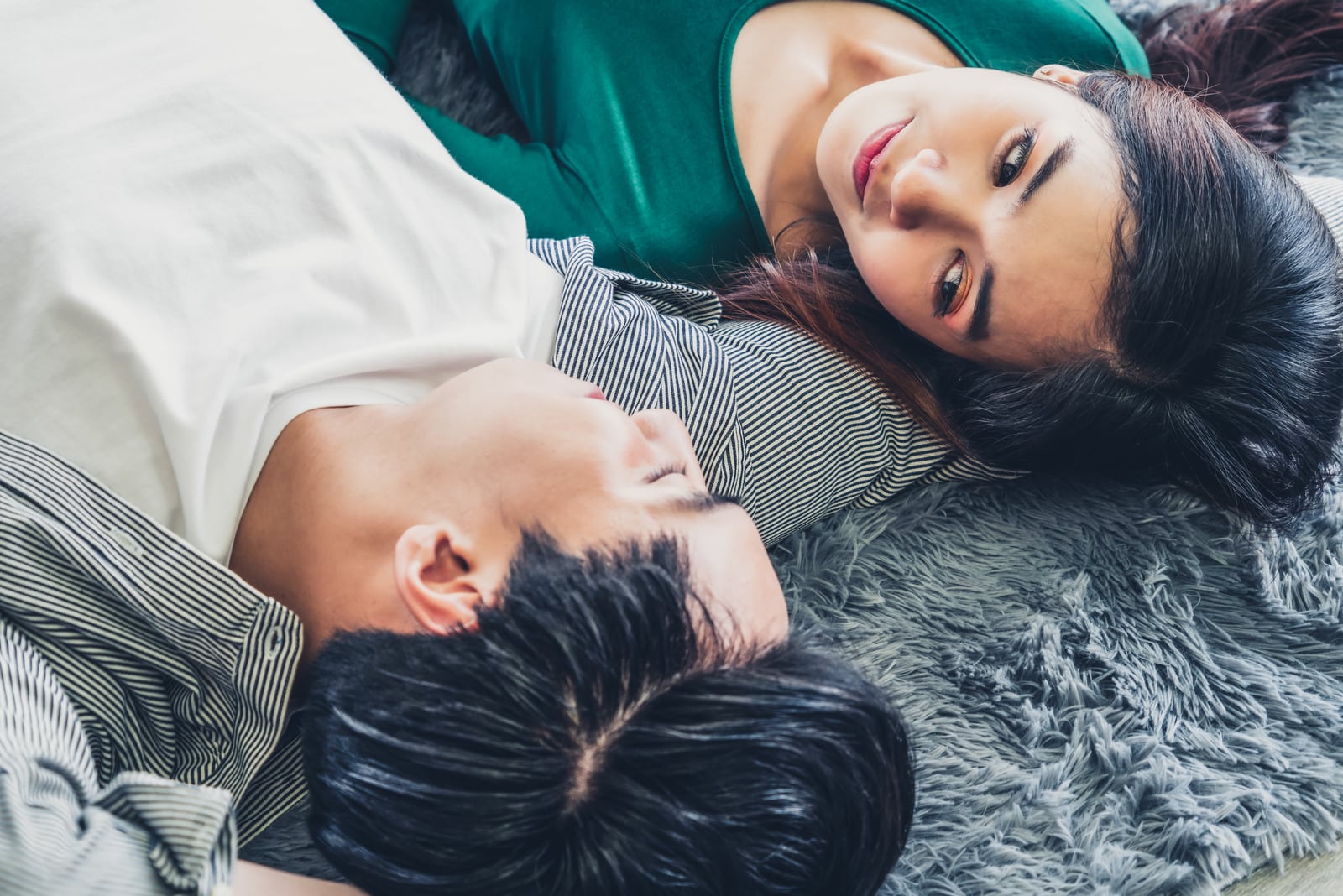 couple lying together on carpet at living room floor