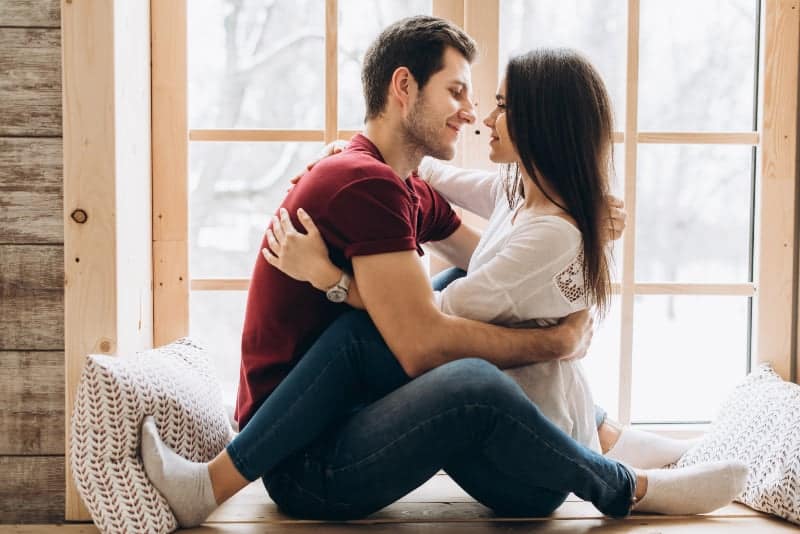 pareja sentada junto a la ventana mirándose