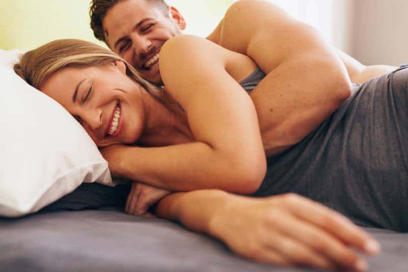 linda pareja joven acostado en la cama y sonriendo