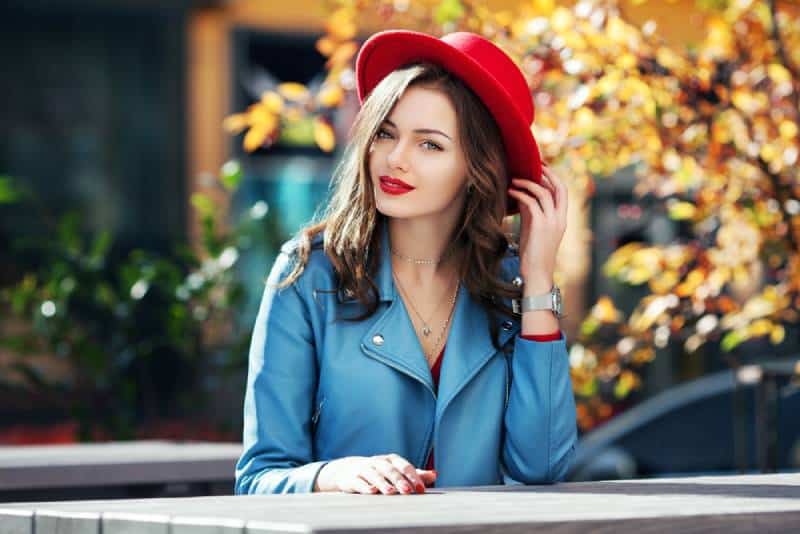 rapariga sorridente e feliz com lábios vermelhos usando um chapéu vermelho elegante