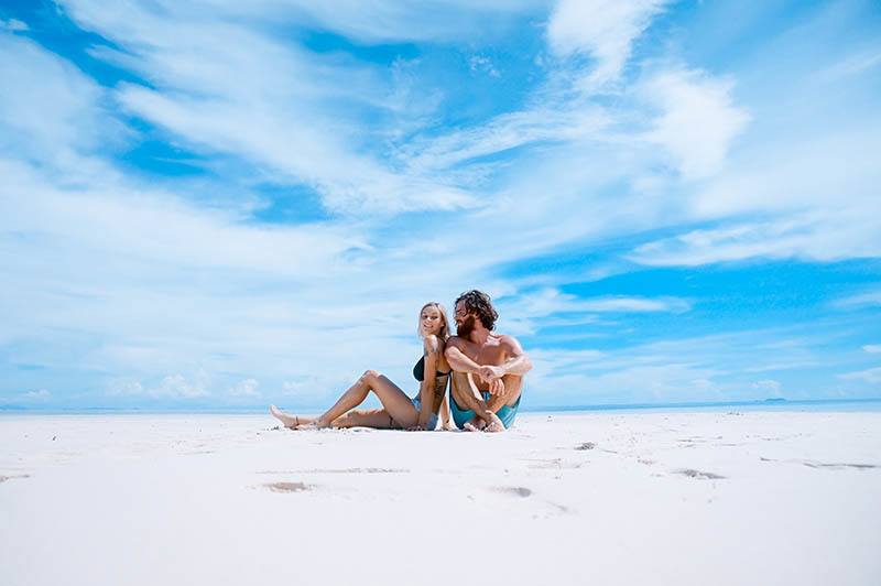 uomo e donna seduti sulla spiaggia durante il giorno