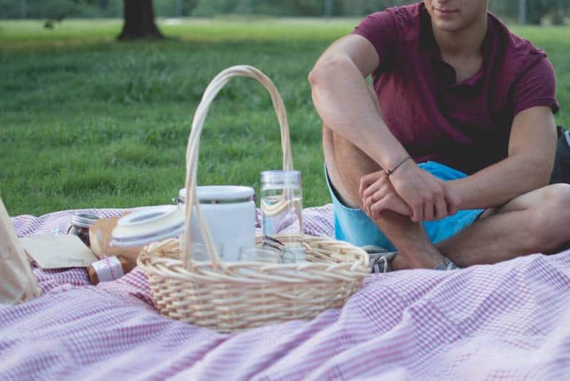 man sitting near basket picnic time