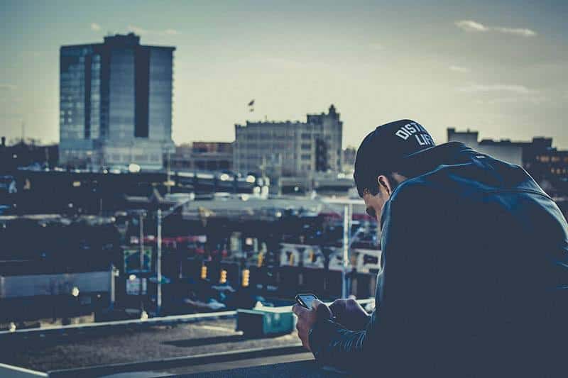 man typing on his phone on balcony