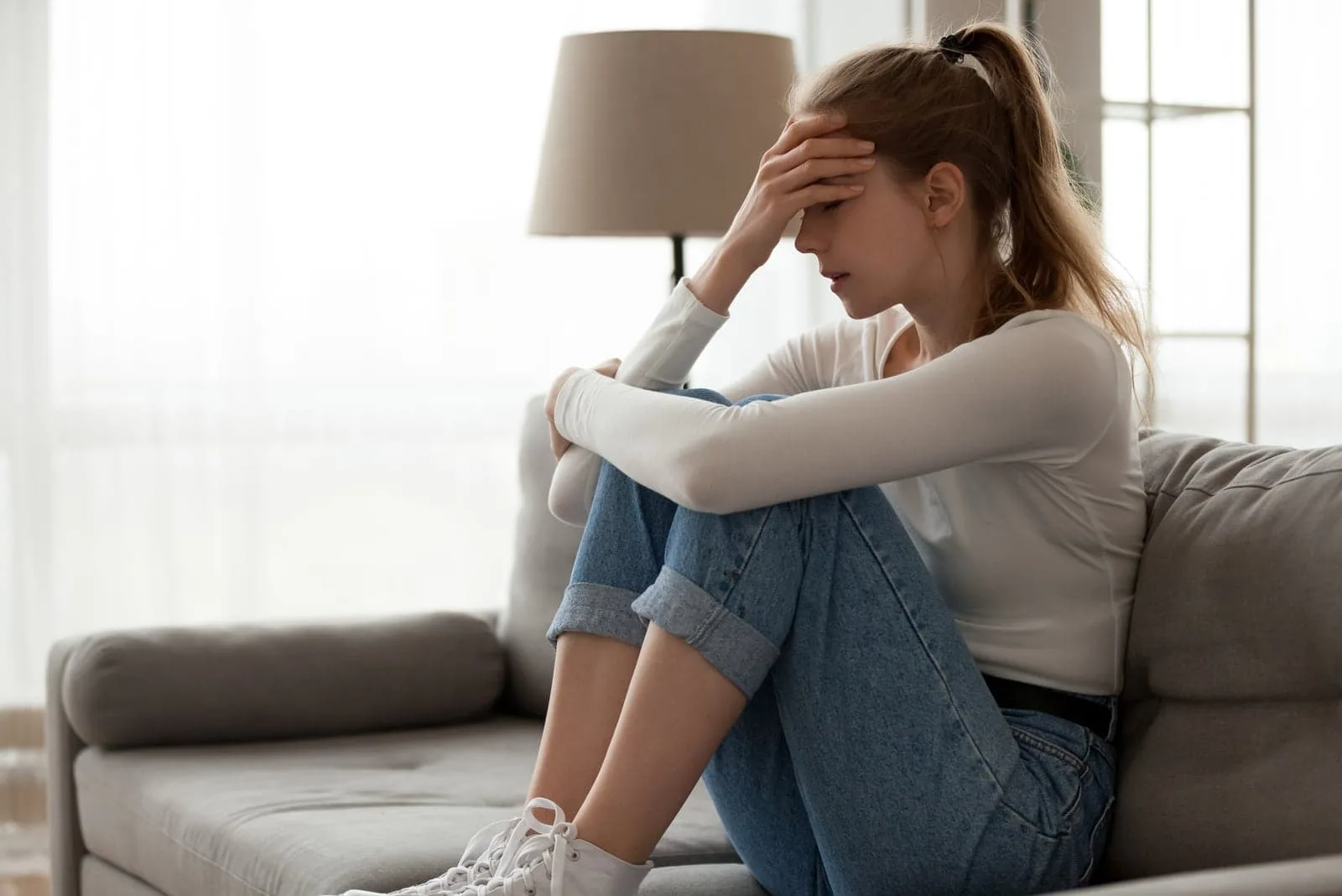 sad woman sitting on the couch and thinking